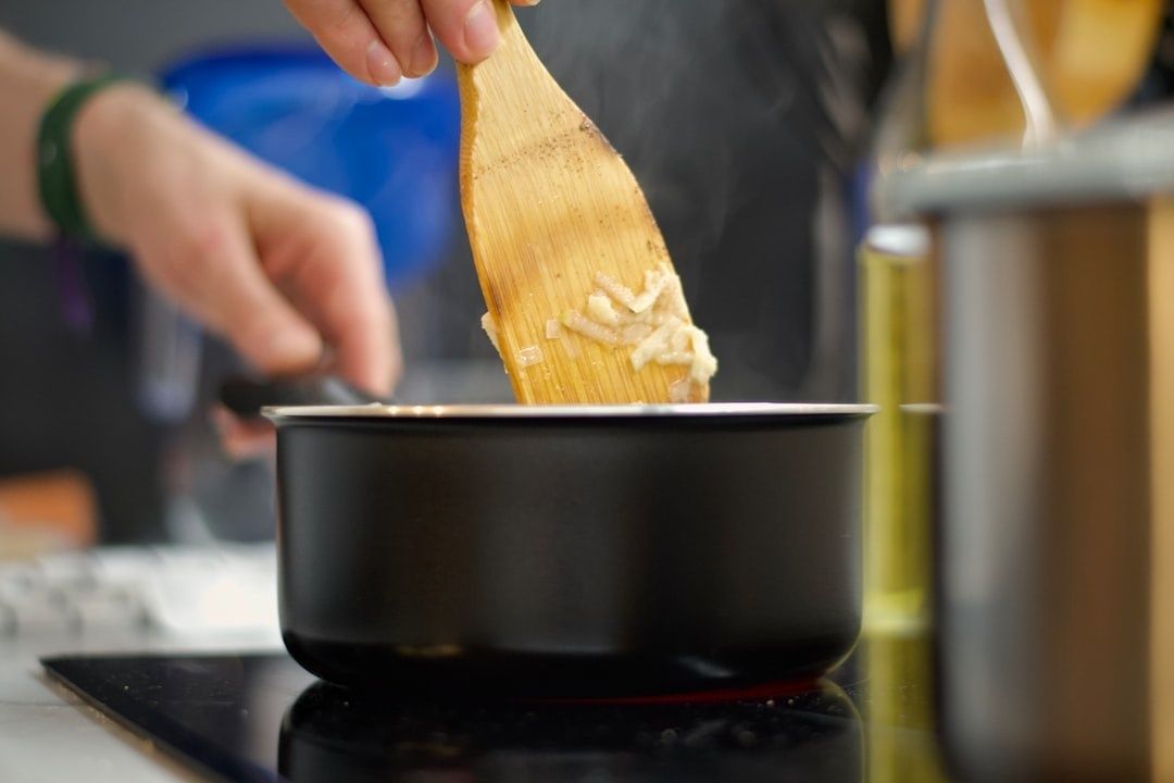 Wooden spoon stirring a steaming saucepan of risotto ingredients
